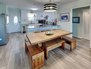 A modern kitchen with a central island, wooden benches, and pendant lighting. - Sellers by Topsail Realty (Holly Ridge)