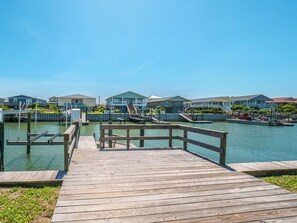 A wooden pier leading to a marina with several houses and boats.