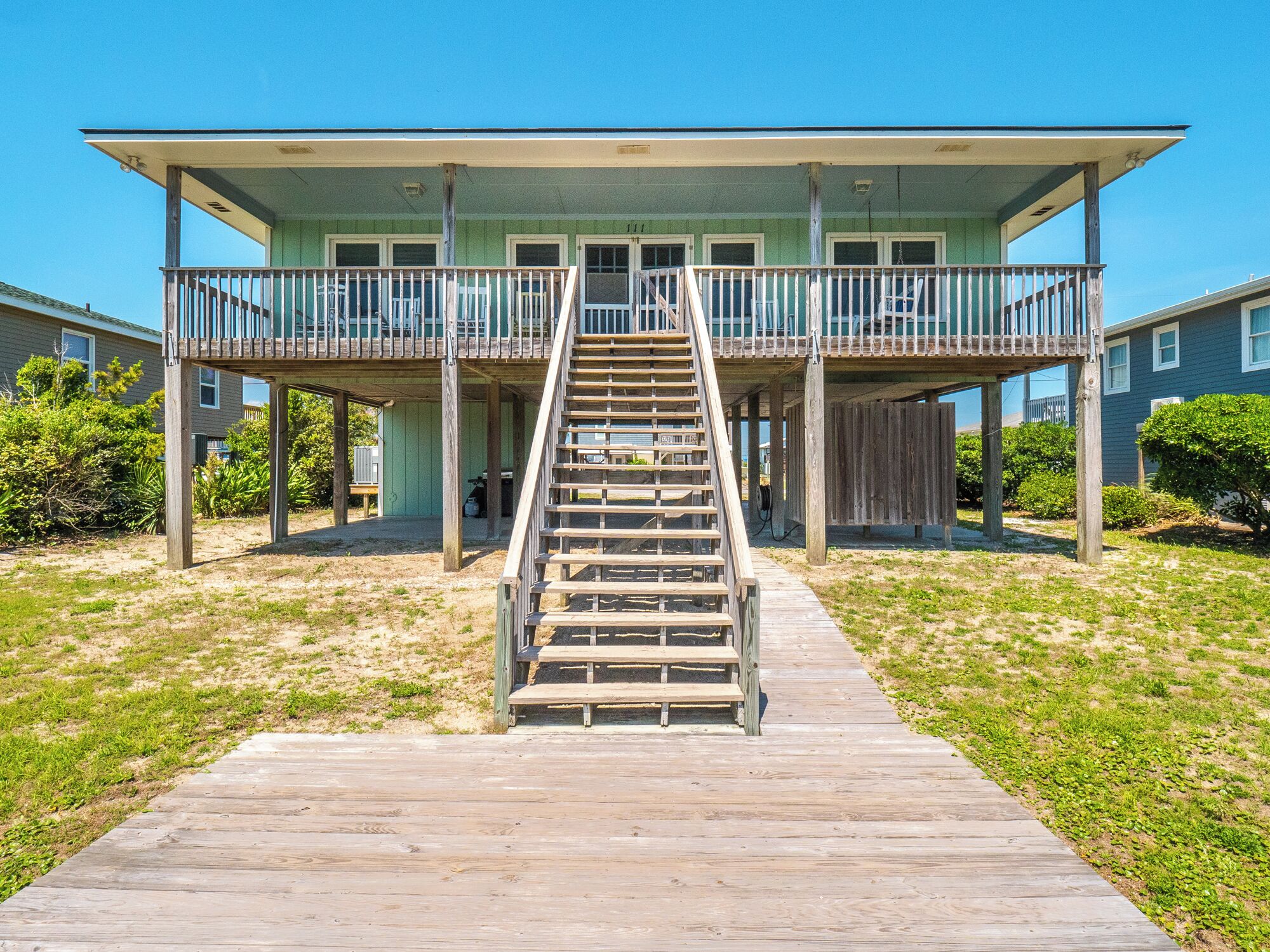A beachfront house with a wooden staircase leading to a balcony.