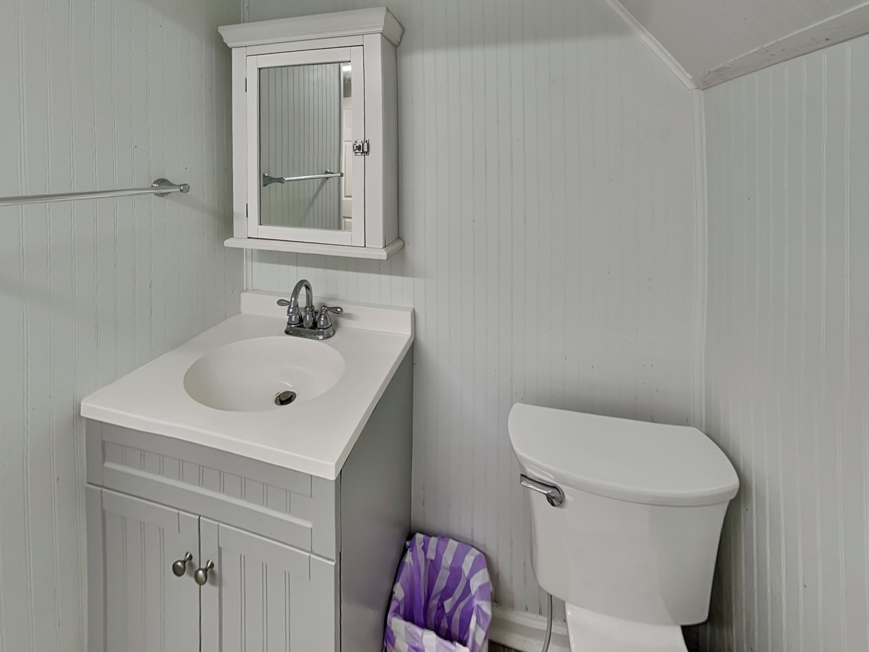 A bathroom with a white sink, a mirror above it, and a toilet.