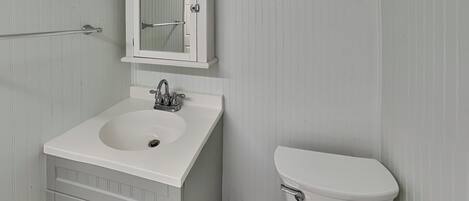 A bathroom with a white sink, a mirror above it, and a toilet.