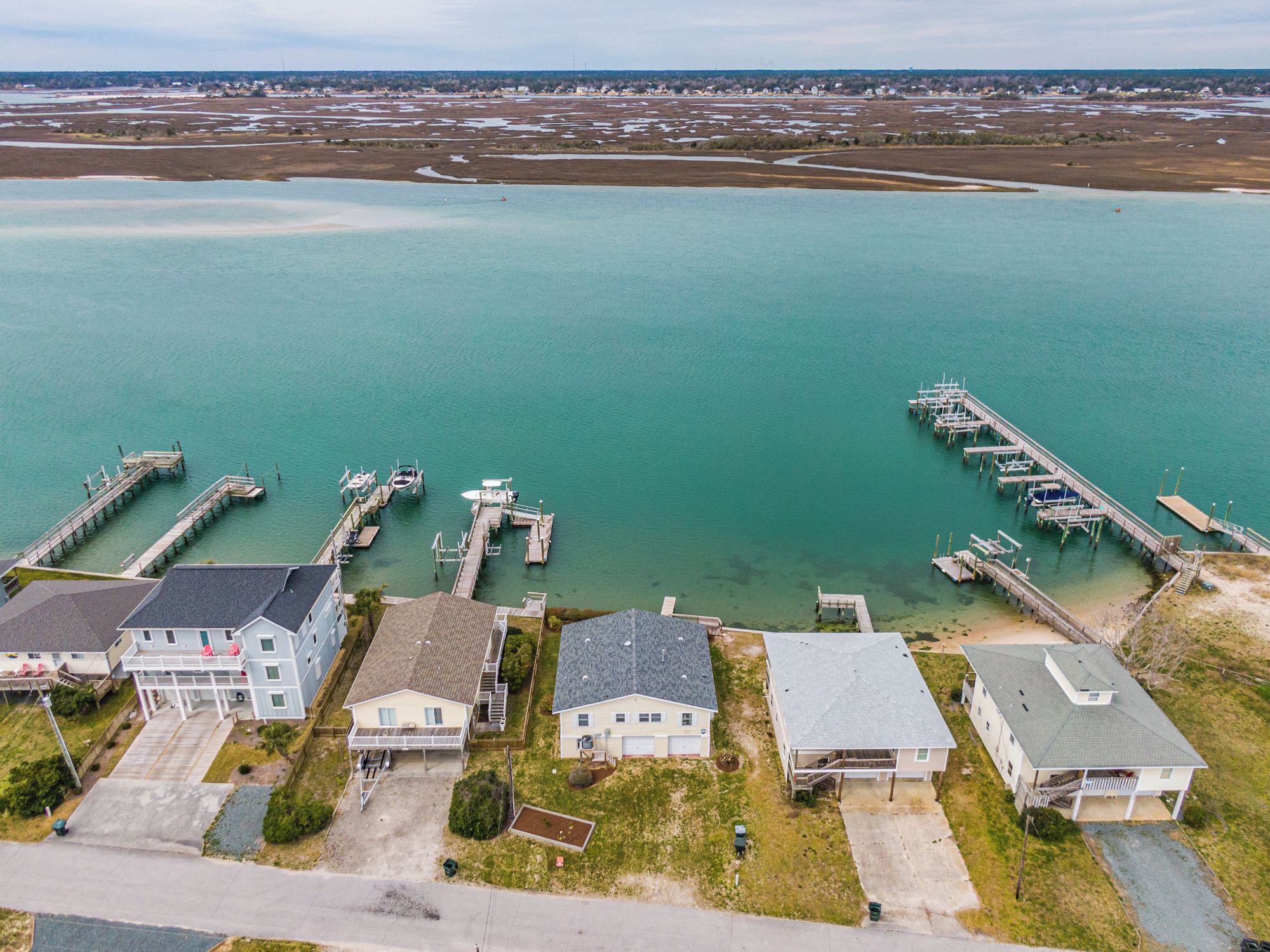 An aerial view of a coastal area with several houses and a marina with docks.