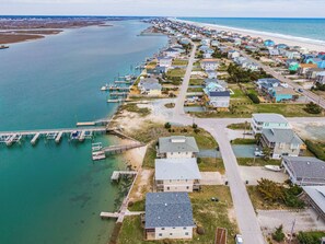 An aerial view of a coastal residential area with houses, a pier, and a beach. - Lindy-B by Topsail Realty (Holly Ridge)