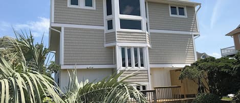 Una casa de dos pisos con un amplio ventanal y un pequeño porche.
