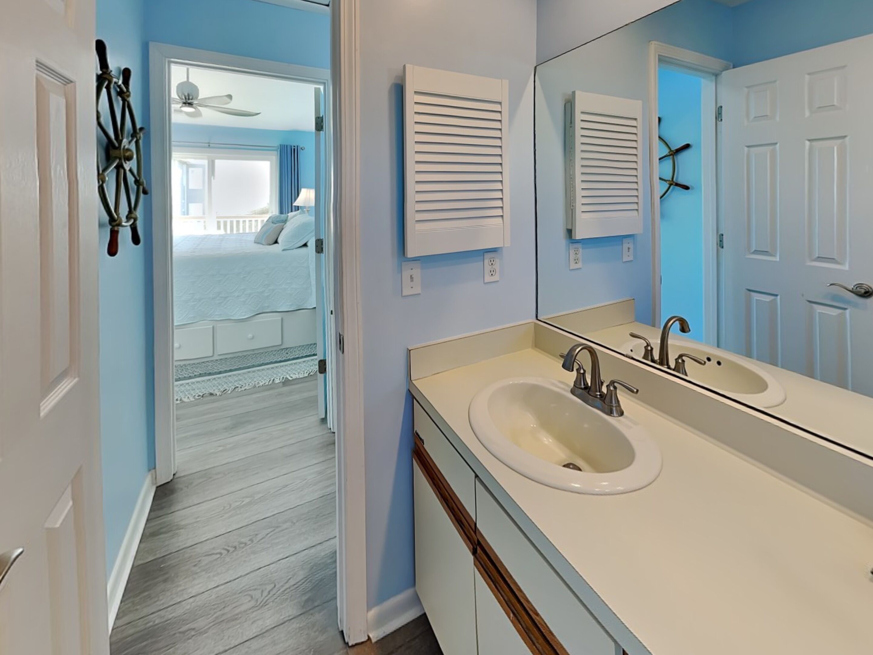 A bathroom with a double sink, a large mirror, and a ceiling fan.