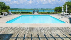 Une piscine avec une terrasse en bois, des chaises longues et une vue sur l’océan.