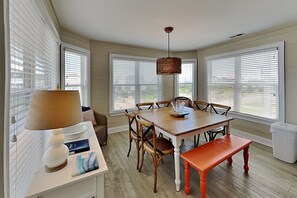Een eetgedeelte met een houten tafel, stoelen, een bank, een lamp en een hangende lamp.