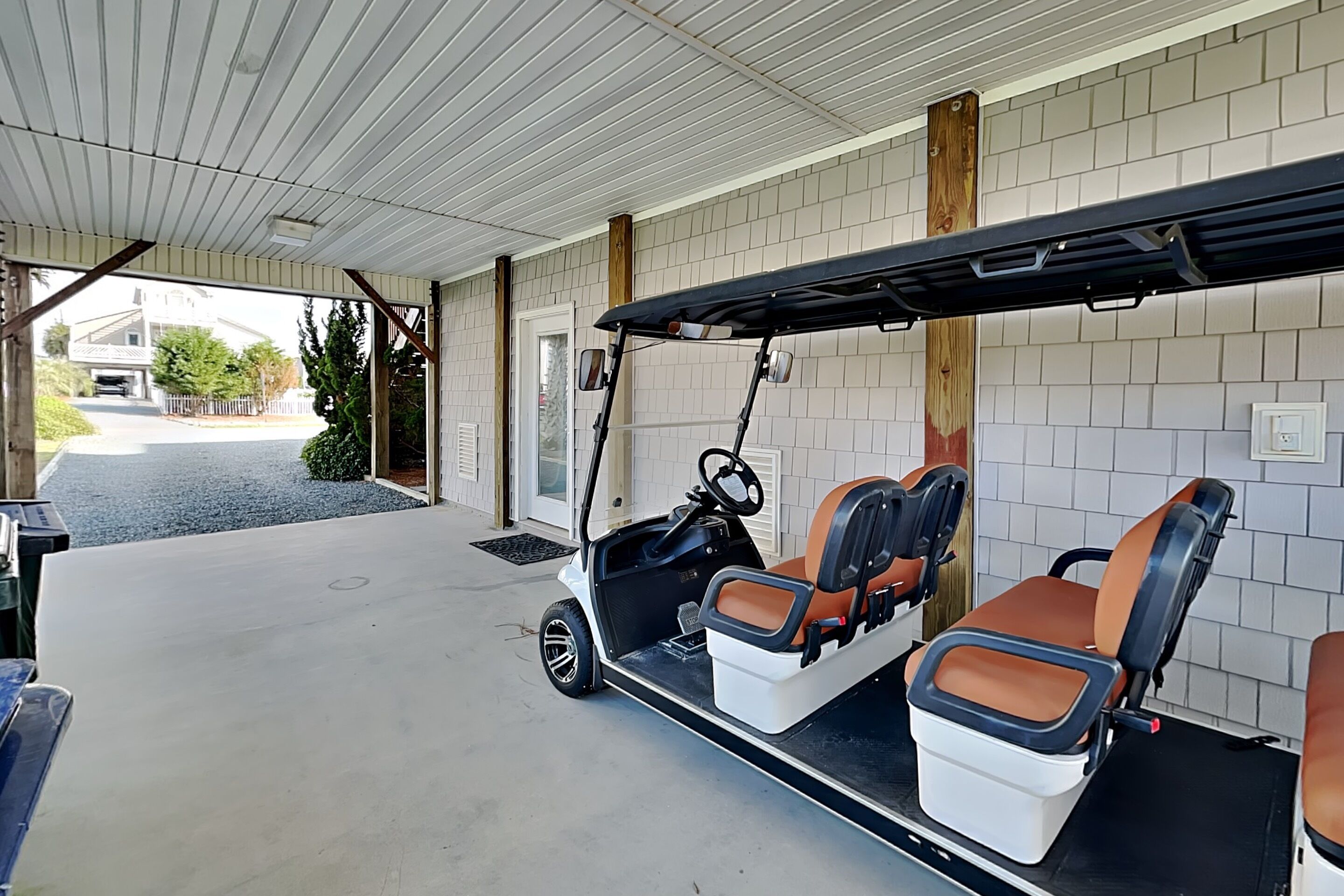A covered parking area with a golf cart and a covered seating area.