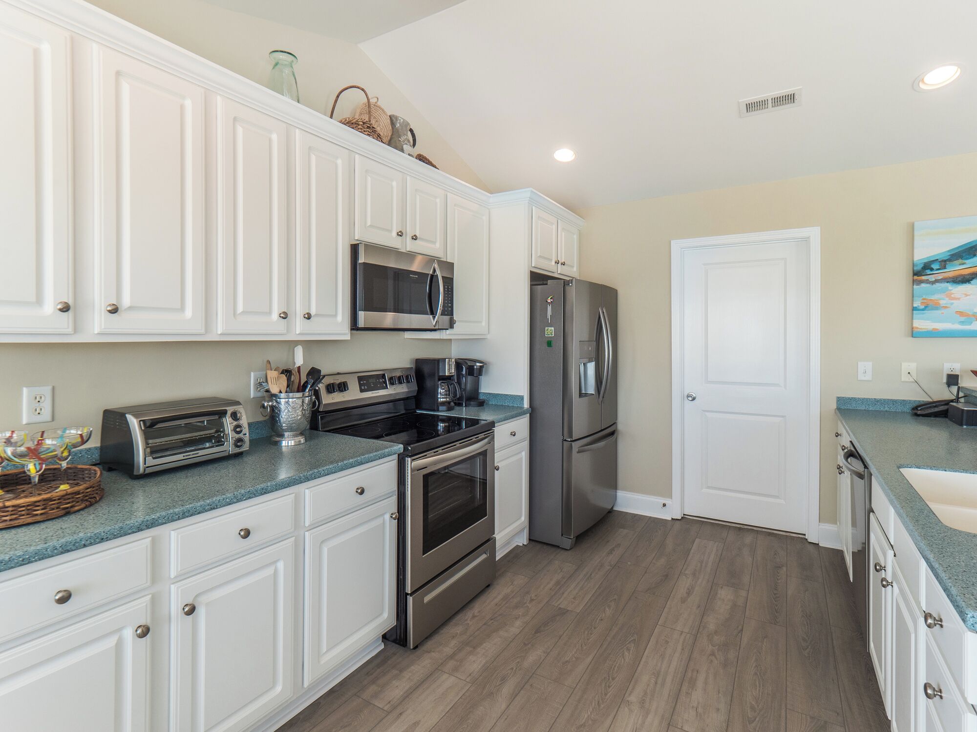 A modern kitchen with white cabinets, stainless steel appliances, and a blue countertop.
