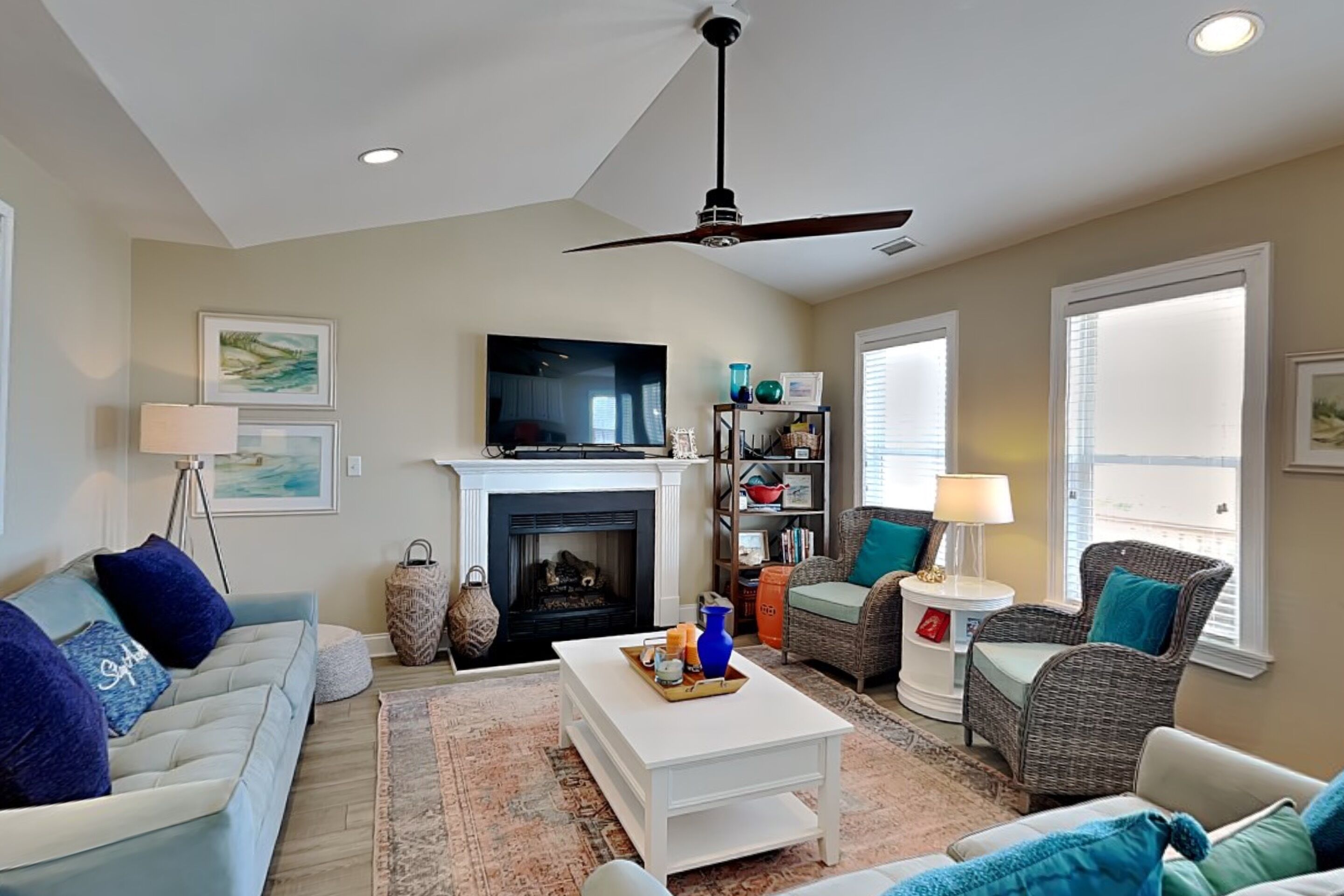 A living room with a fireplace, a ceiling fan, a television, and a bookshelf.