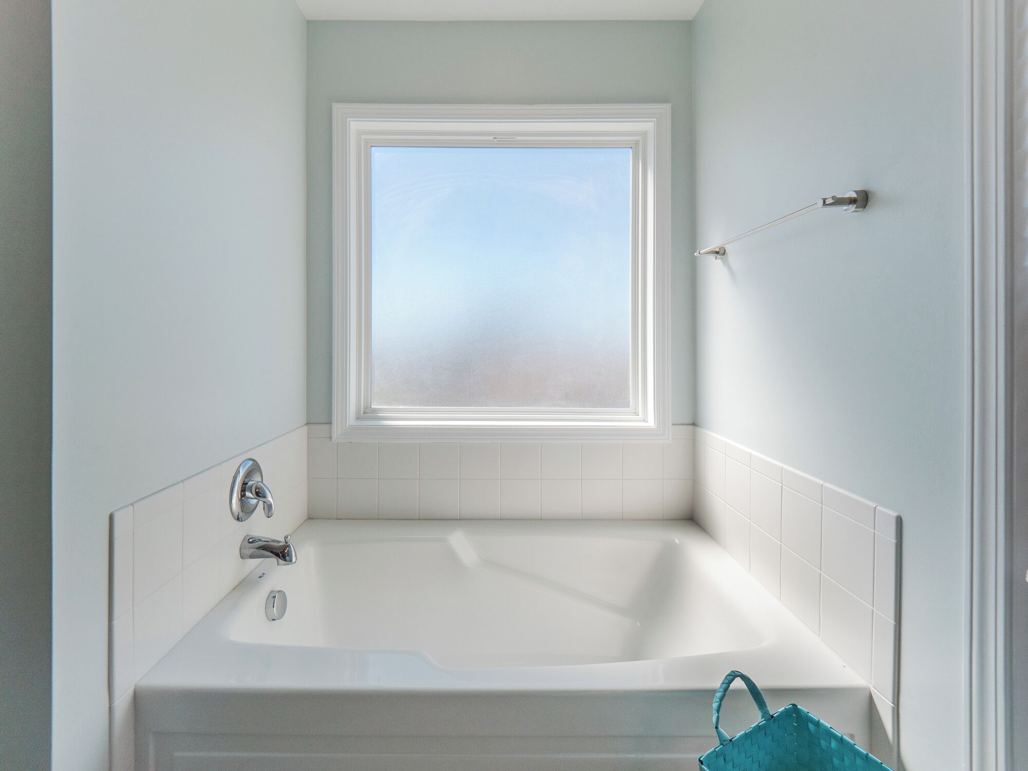 Un baño con bañera, ventana y toallero.