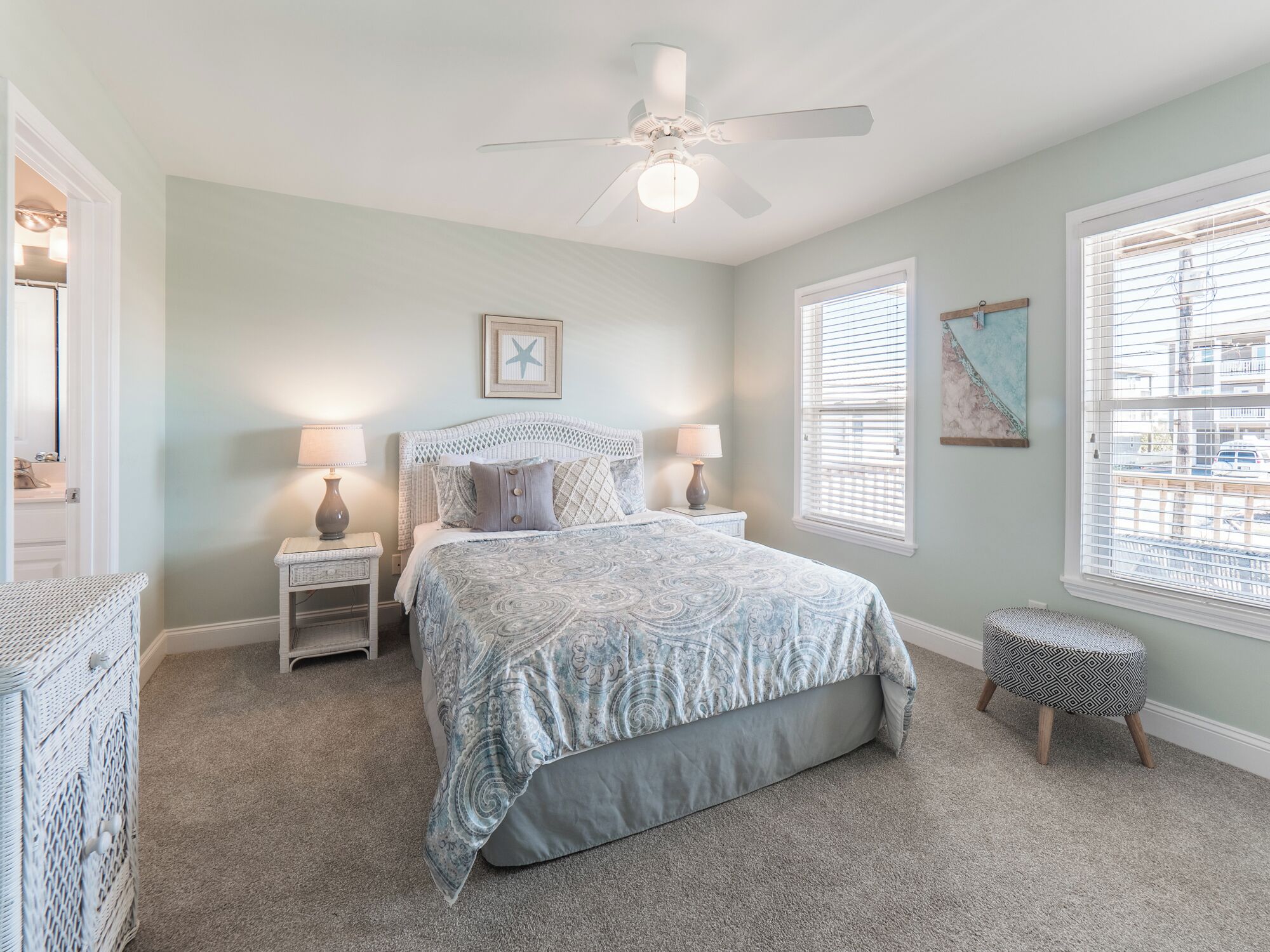 A bedroom with a bed, two bedside tables, a ceiling fan, and a window with blinds.