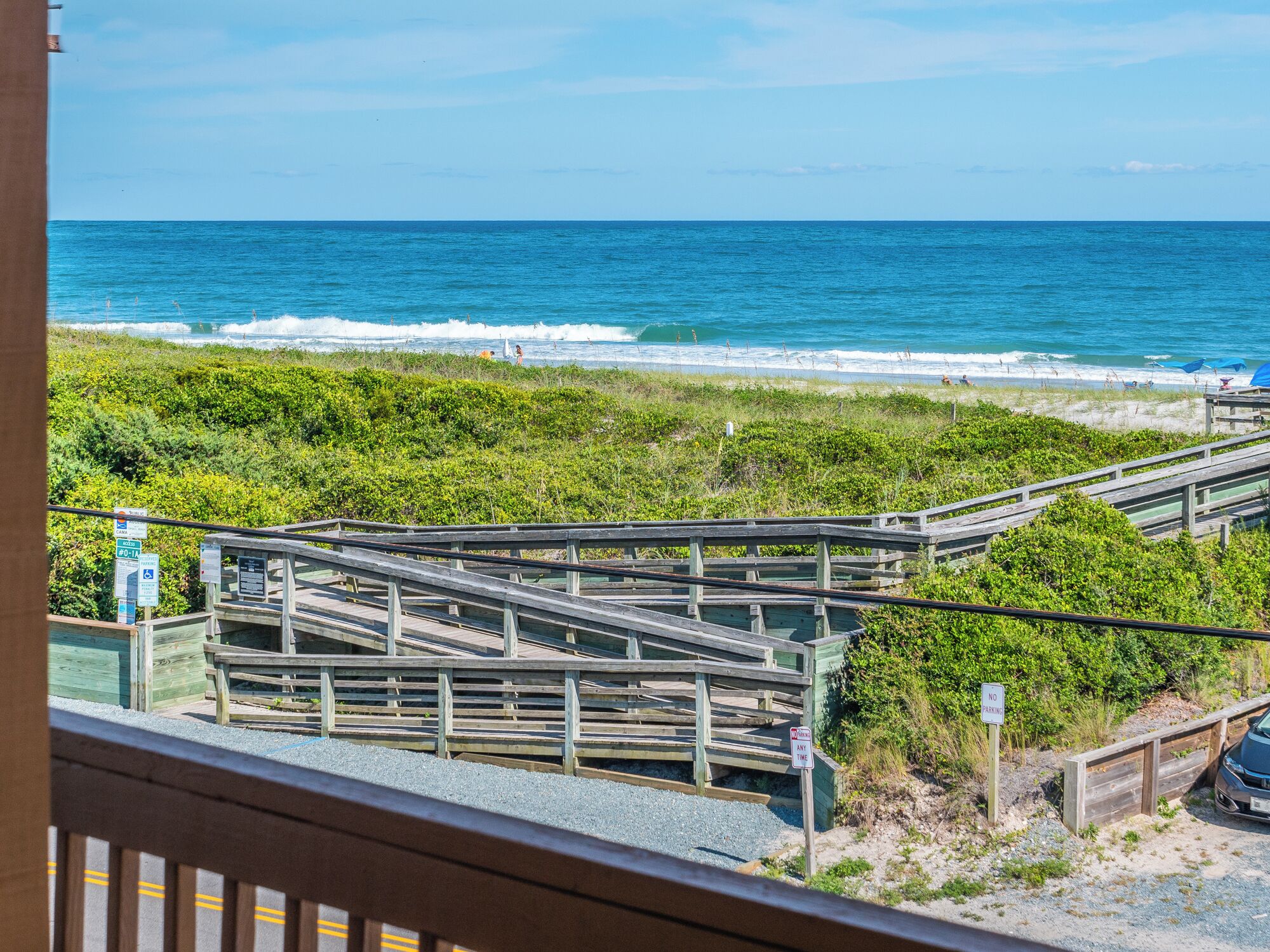 A wooden boardwalk leading to a beach with ocean views.