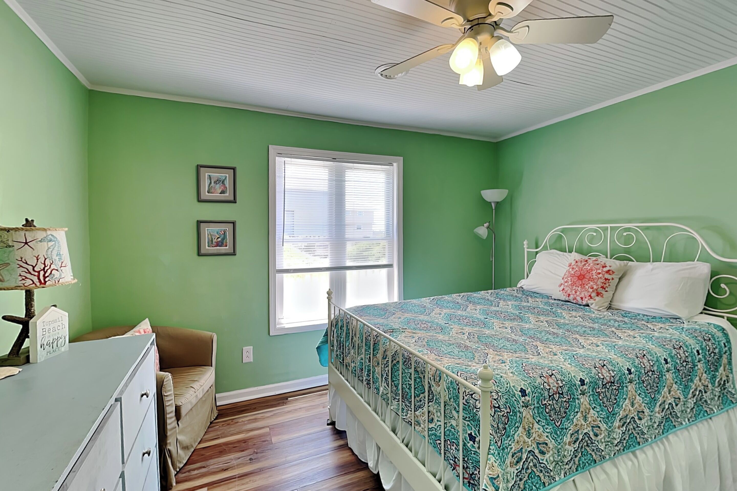 A bedroom with a bed, a dresser, a chair, a window with blinds, and a ceiling fan.