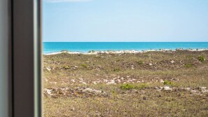 A beach view with a clear sky and a sandy area with sparse vegetation. - Slow Motion #8A by Topsail Realty (Holly Ridge)