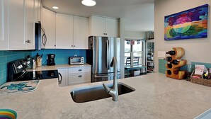 A modern kitchen with white cabinets, stainless steel appliances, and a marble countertop. - Slow Motion #8A by Topsail Realty (Holly Ridge)