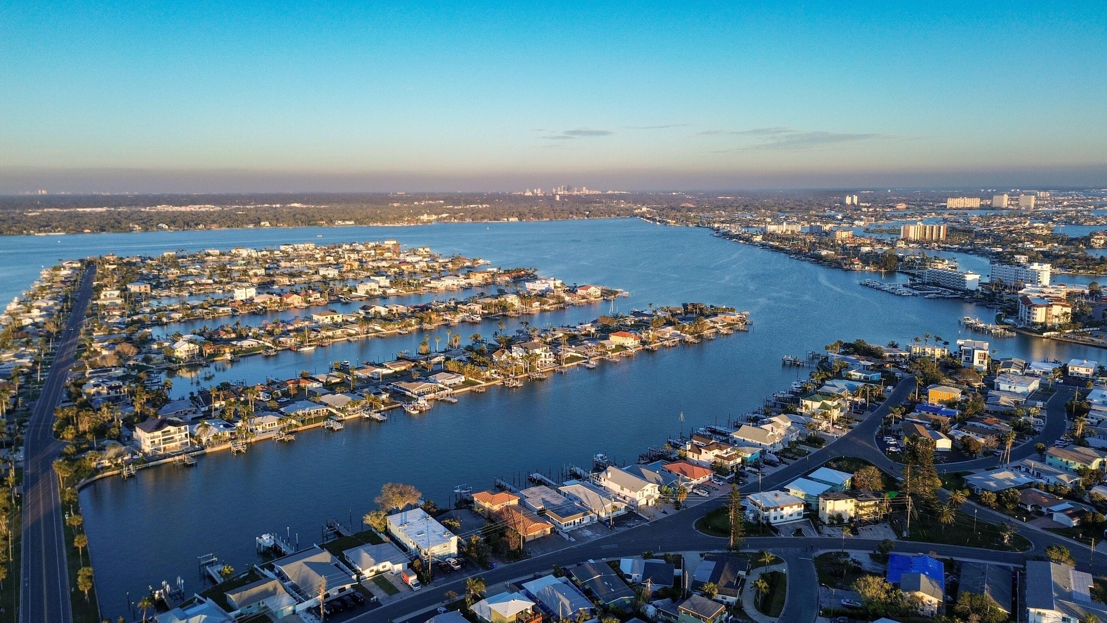 Vista aérea de una zona residencial costera con numerosas casas y barcos, conectada por carreteras y vías fluviales.