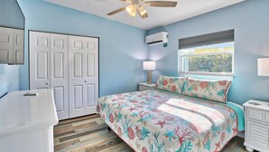 A bedroom with a bed, a ceiling fan, a window with blinds, a nightstand, and a dresser. - Shore La Vie (Treasure Island)