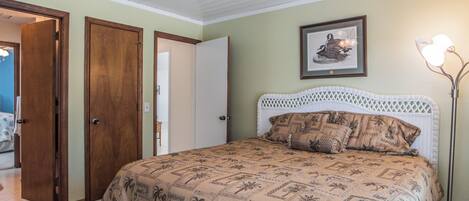 Una camera da letto con un letto, una ventola a soffitto e un quadro appeso al muro.