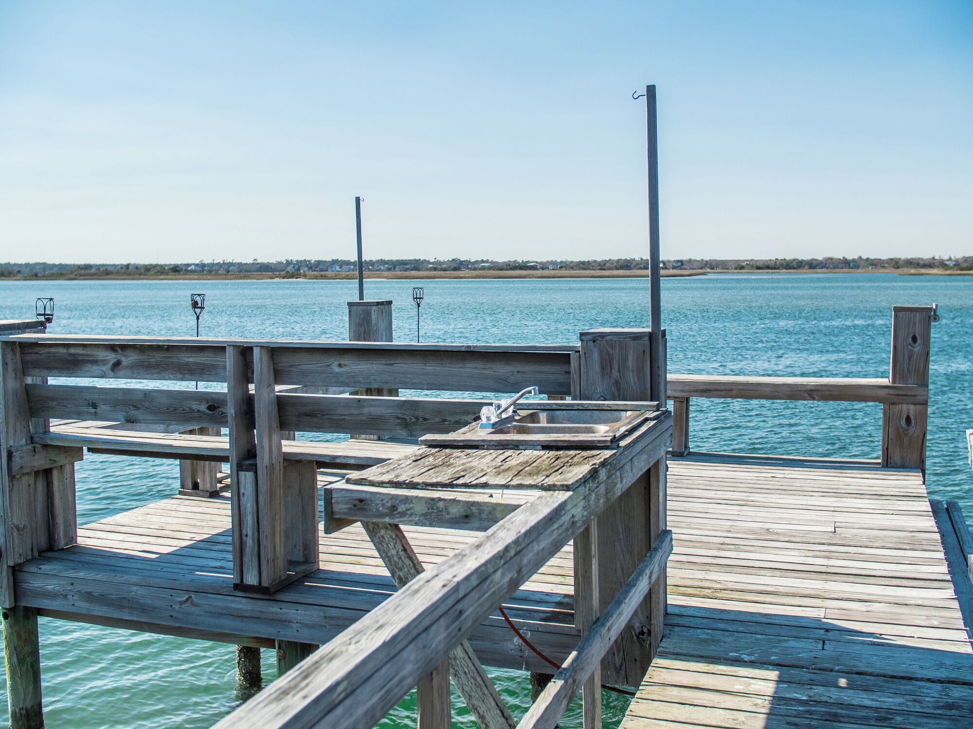 A wooden pier extending into a calm body of water with a clear sky above.