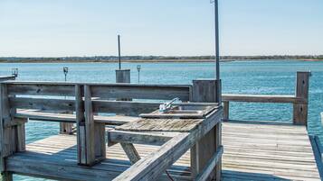 A wooden pier extending into a calm body of water with a clear sky above.