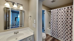 A bathroom with a white sink, mirror, and shower curtain. - Luna Escape by Topsail Realty (Holly Ridge)