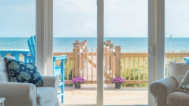 Una habitación con vistas al océano a través de grandes puertas correderas de vidrio.