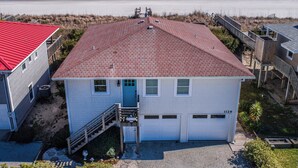 Ein Strandhaus mit rotem Dach, blauer Haustür und einer Garage.
