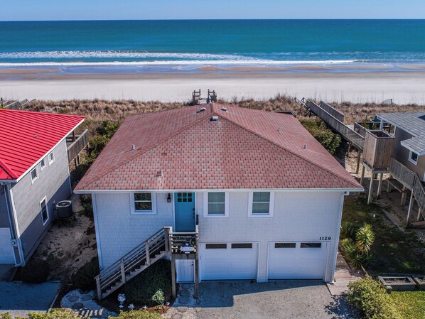 A beachfront house with a red roof, a blue front door, and a garage. - Tournesol by Topsail Realty (Holly Ridge)
