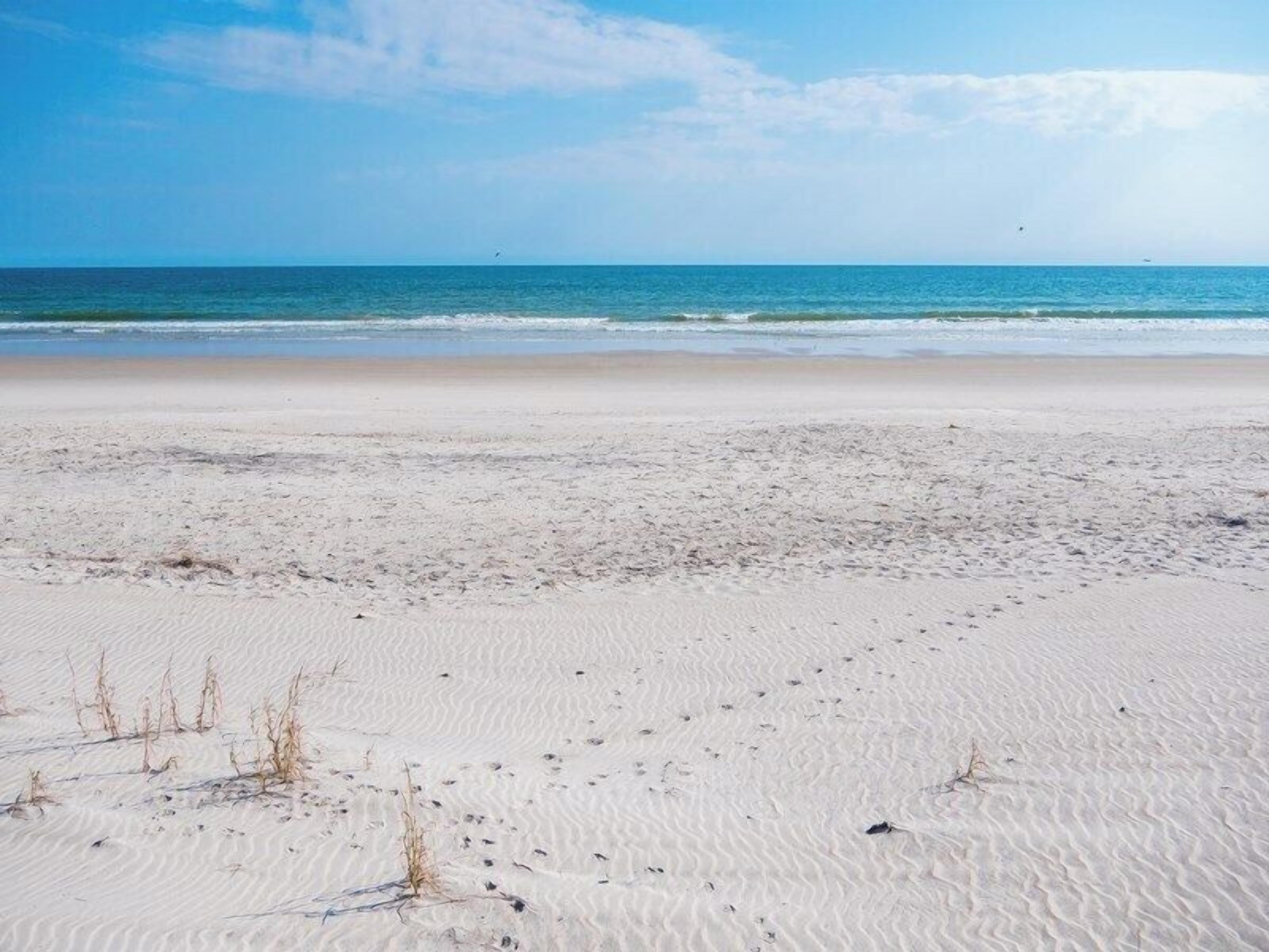 A sandy beach with gentle waves and a clear sky.