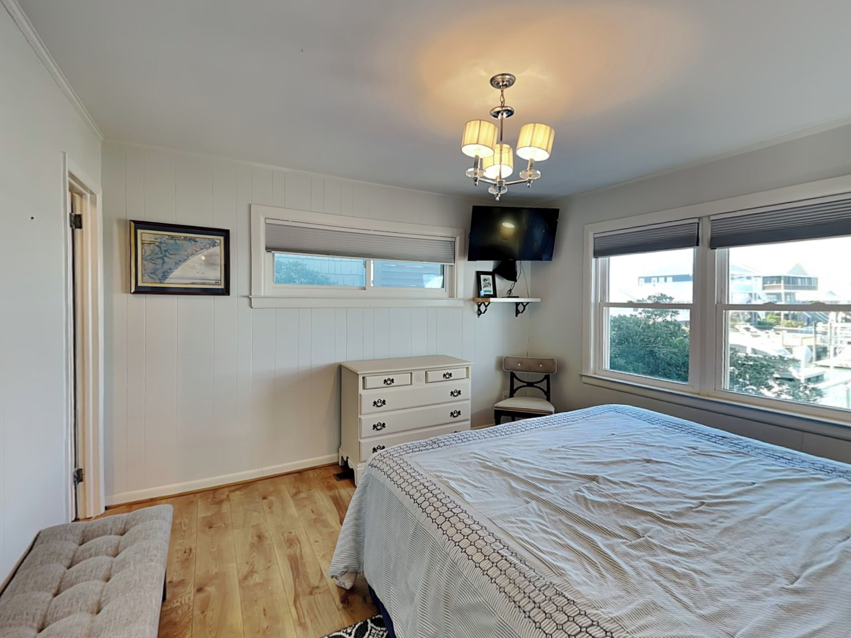 Ein Schlafzimmer mit Bett, Schminktisch, Sessel, Fernseher und einem Fenster mit Blick.