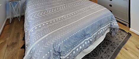 Un dormitorio con cama, cómoda, mesita de noche, lámpara y espejo.