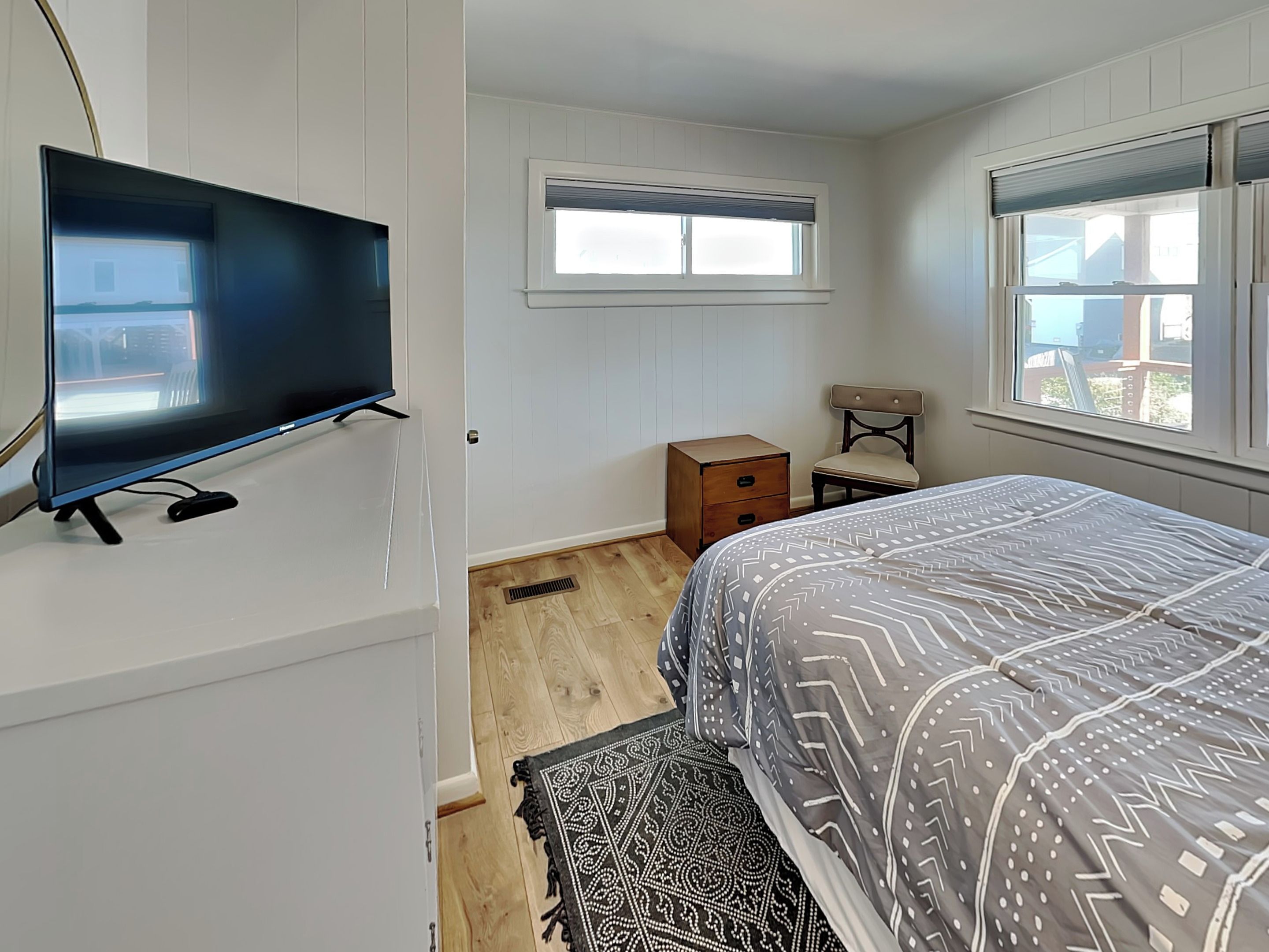 A bedroom with a bed, a TV, a window, and a nightstand.