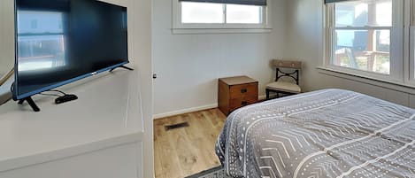 Ein Schlafzimmer mit Bett, Fernseher, Fenster und Nachttisch.