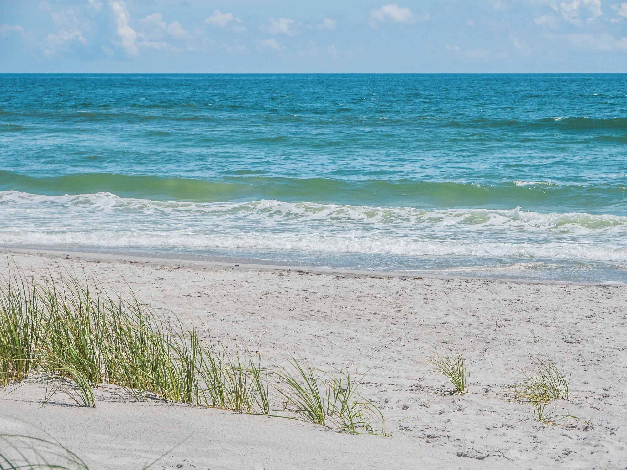 A beach with clear blue water and white sand.
