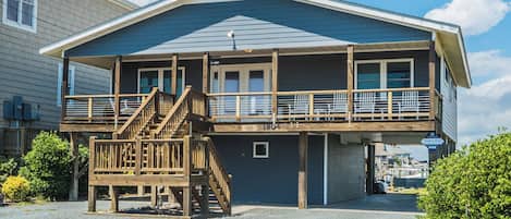 Une maison à deux étages avec un balcon, une terrasse en bois et un garage.
