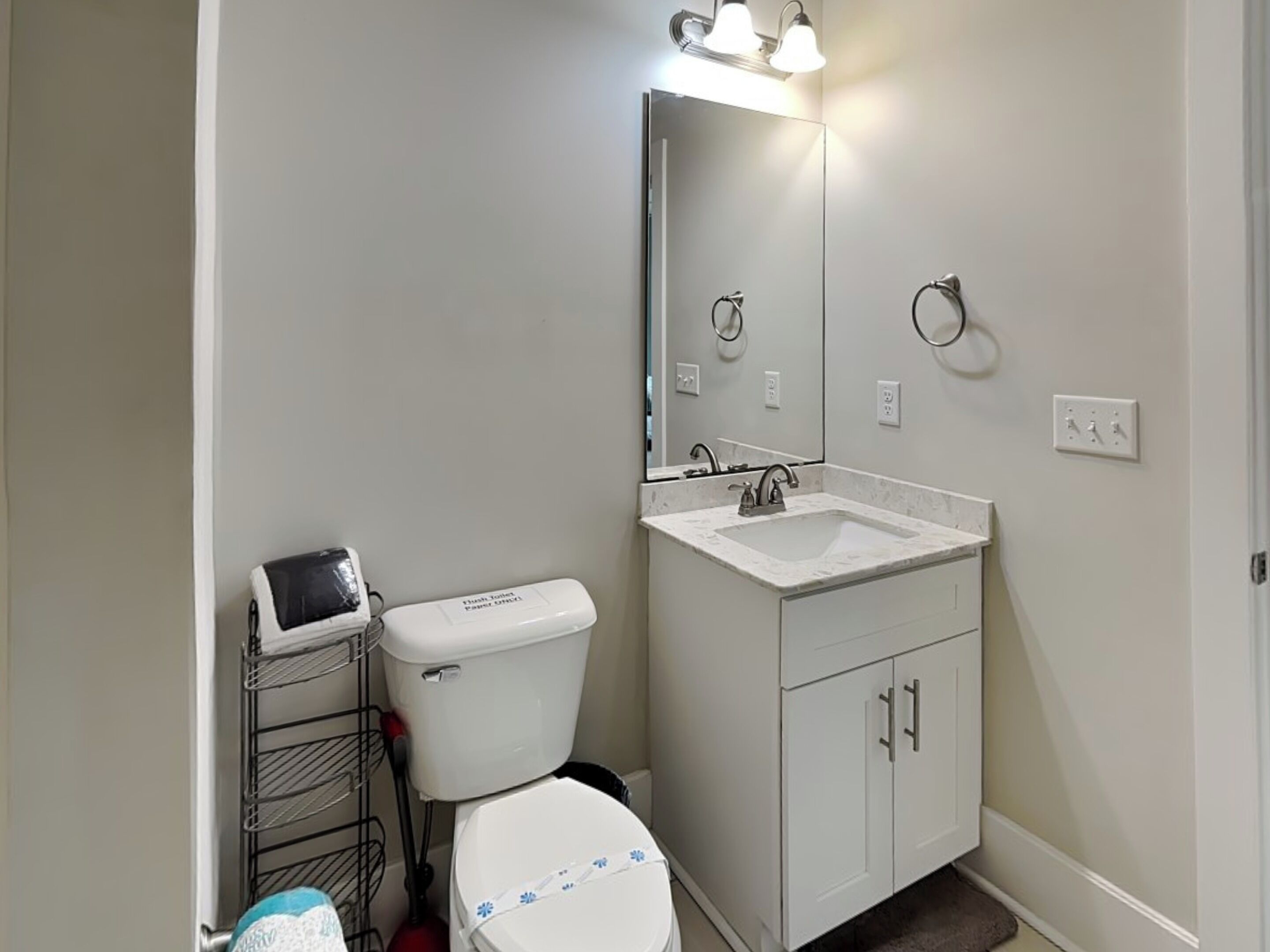 A bathroom with a toilet, a sink, a mirror, and a showerhead.