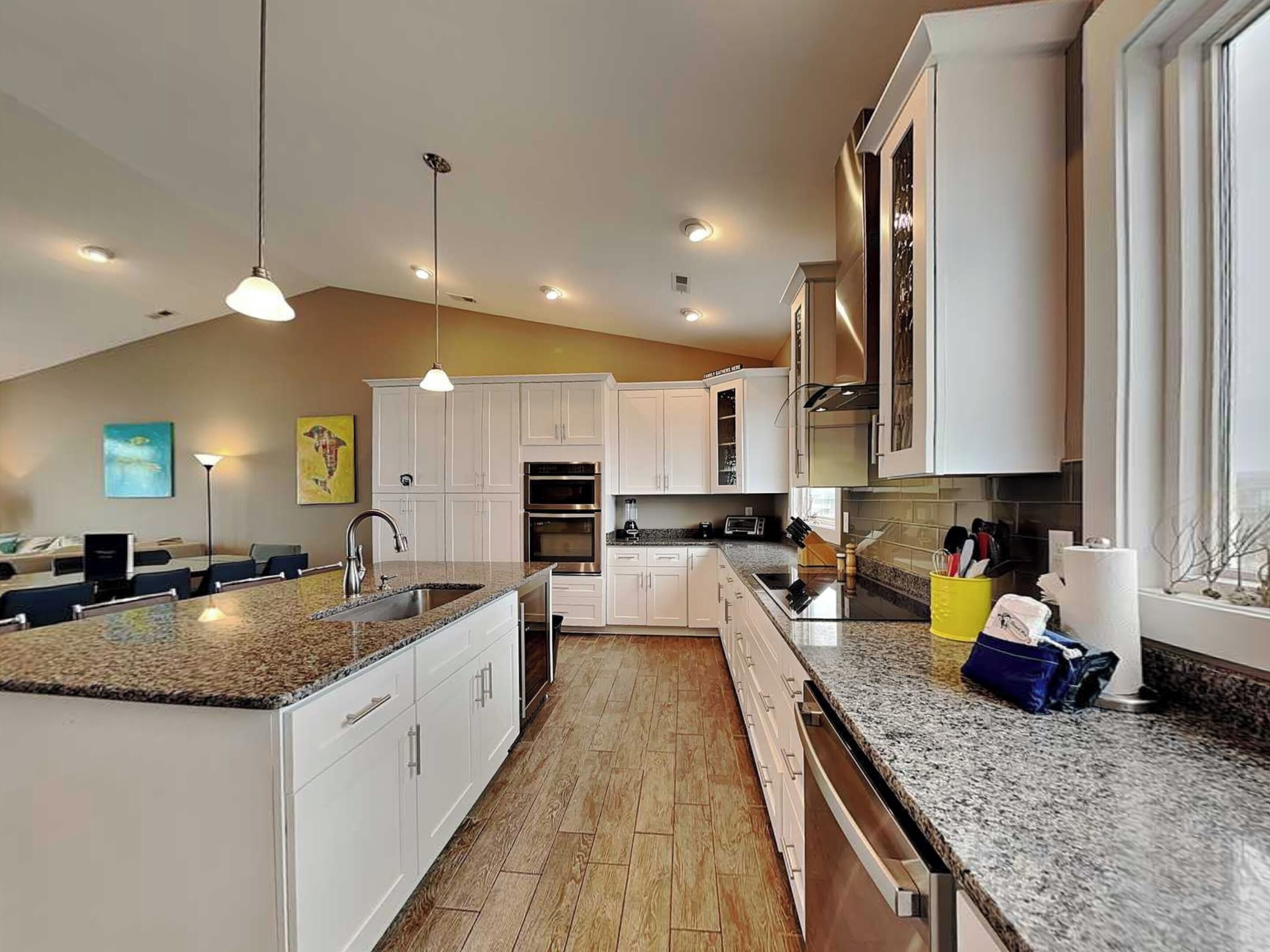 A modern kitchen with white cabinets, granite countertops, and stainless steel appliances.