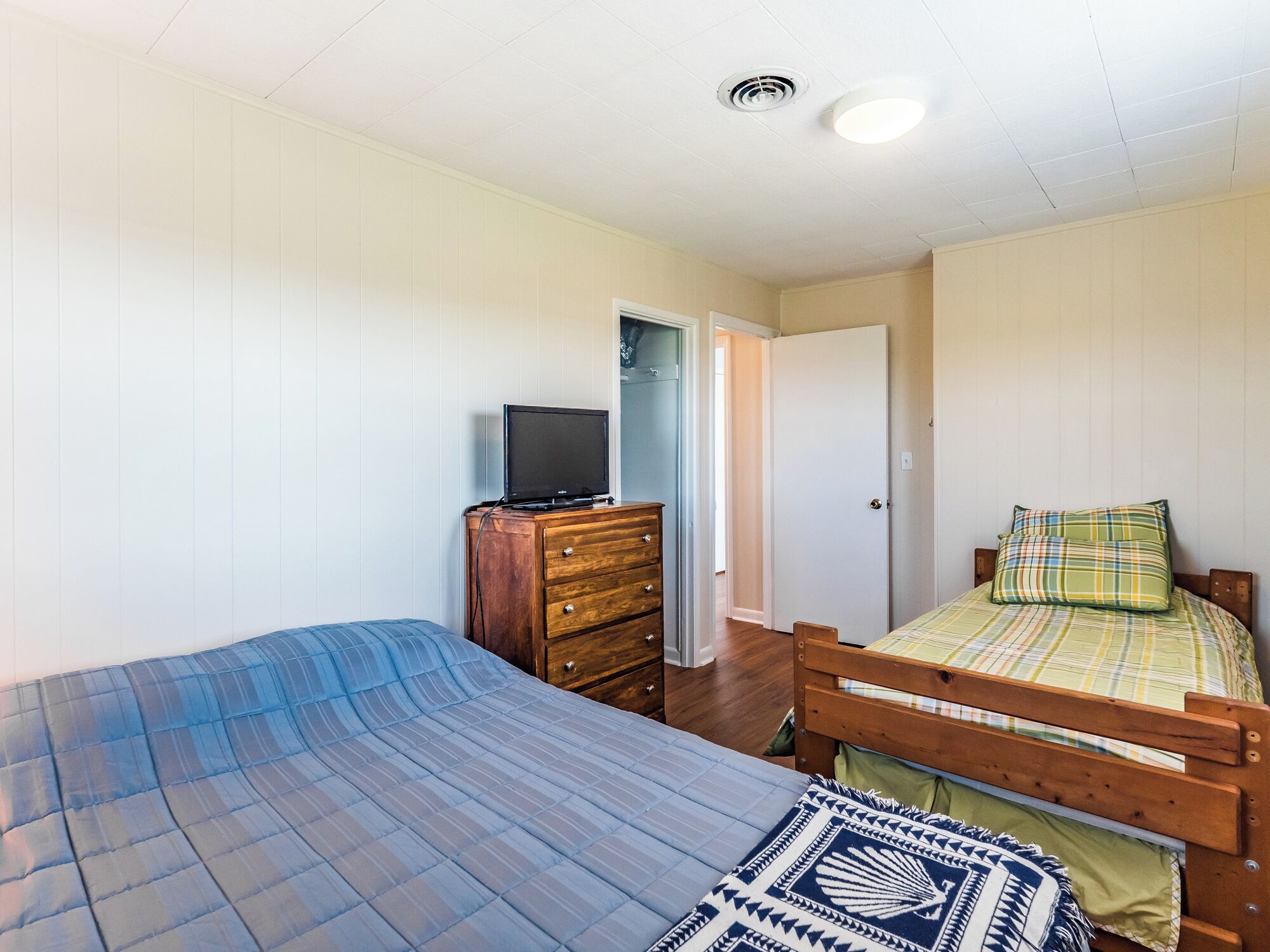 A bedroom with two beds, a dresser, and a television.