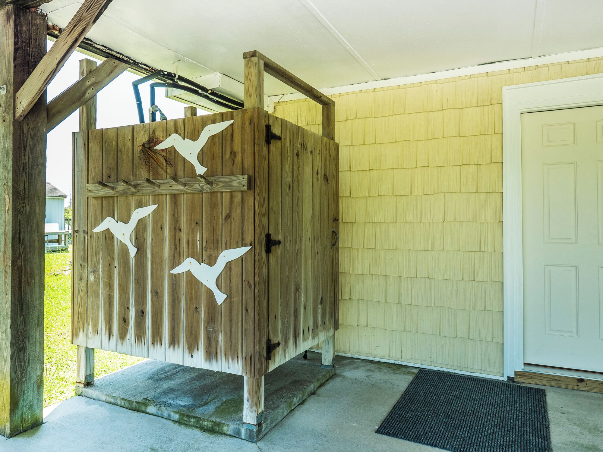 A wooden structure with bird cutouts, a concrete base, and a door to the right.