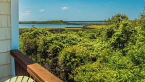 A view from a balcony overlooking a body of water, dense greenery, and a distant shoreline. - Sunset Bay by Topsail Realty (Sneads Ferry)