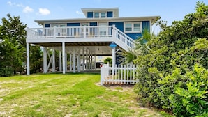 A two-story house with a balcony, a deck, and a well-maintained lawn.