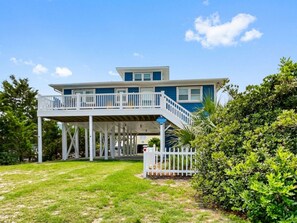 A two-story house with a balcony, a deck, and a well-maintained lawn.