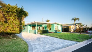 A modern two-story house with a paved driveway and a well-maintained lawn. - Se La Vie (Treasure Island)
