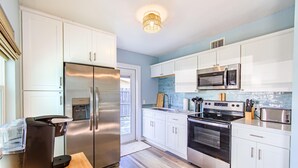 A modern kitchen with white cabinets, stainless steel appliances, and a wooden countertop. - Se La Vie (Treasure Island)