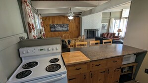 Una cucina compatta con piano cottura, mobili in legno, isola in legno e zona pranzo con sedie.