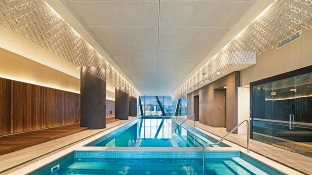 A modern indoor swimming pool with a clear view of the city skyline through large windows.