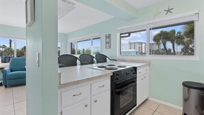 A kitchen with a stove, oven, and large windows. - Crescent Shore 201 (Fort Myers Beach)
