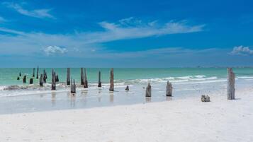 A beach with wooden posts and a lighthouse in the distance.