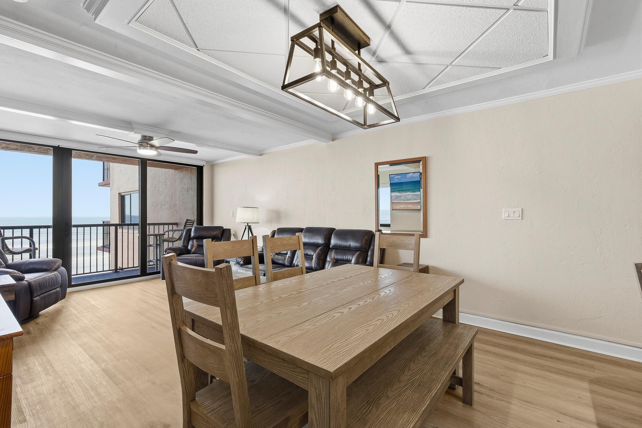 A spacious room with a large wooden table, leather chairs, and a ceiling fan.